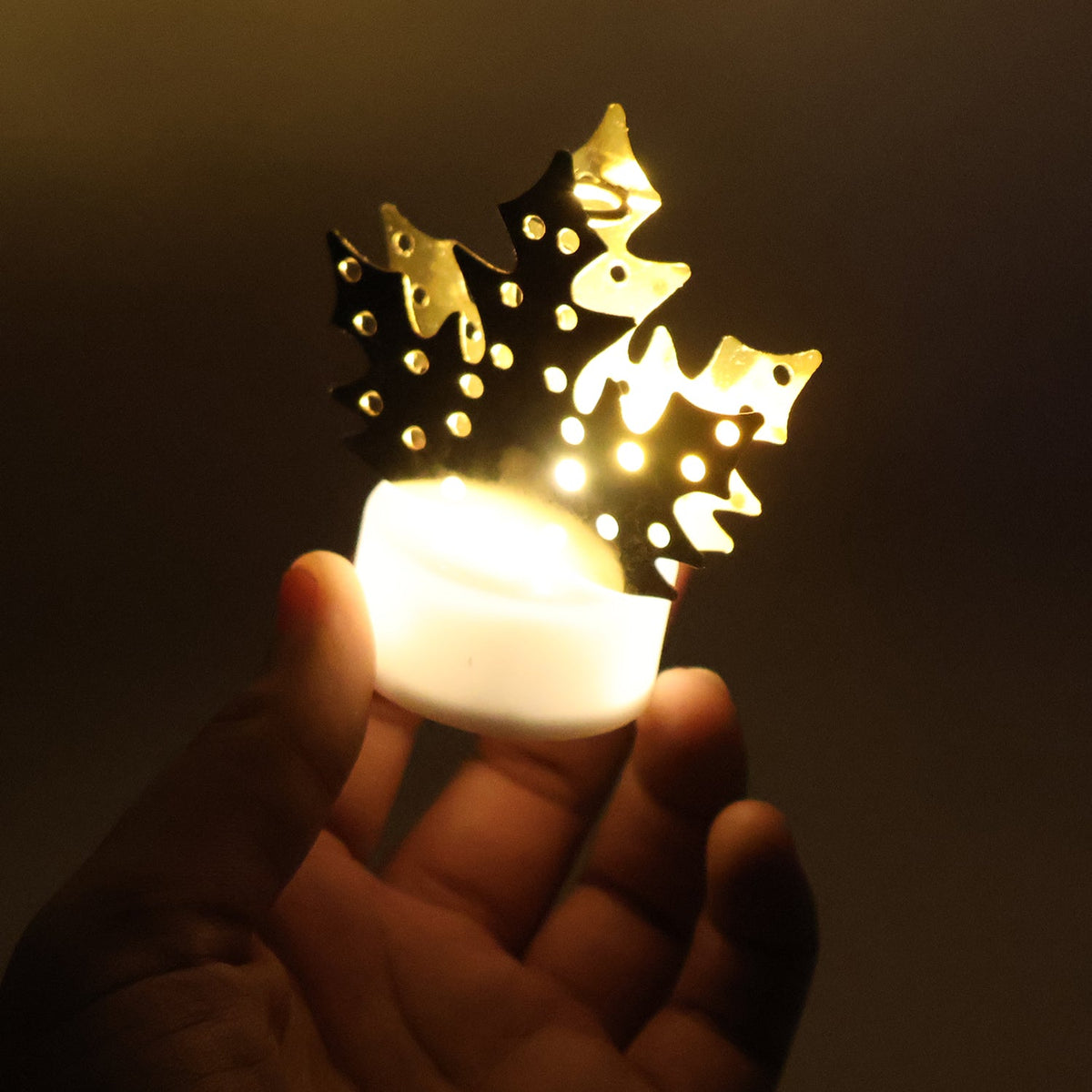 Gold metal leaf diya lamp glowing, held in hand