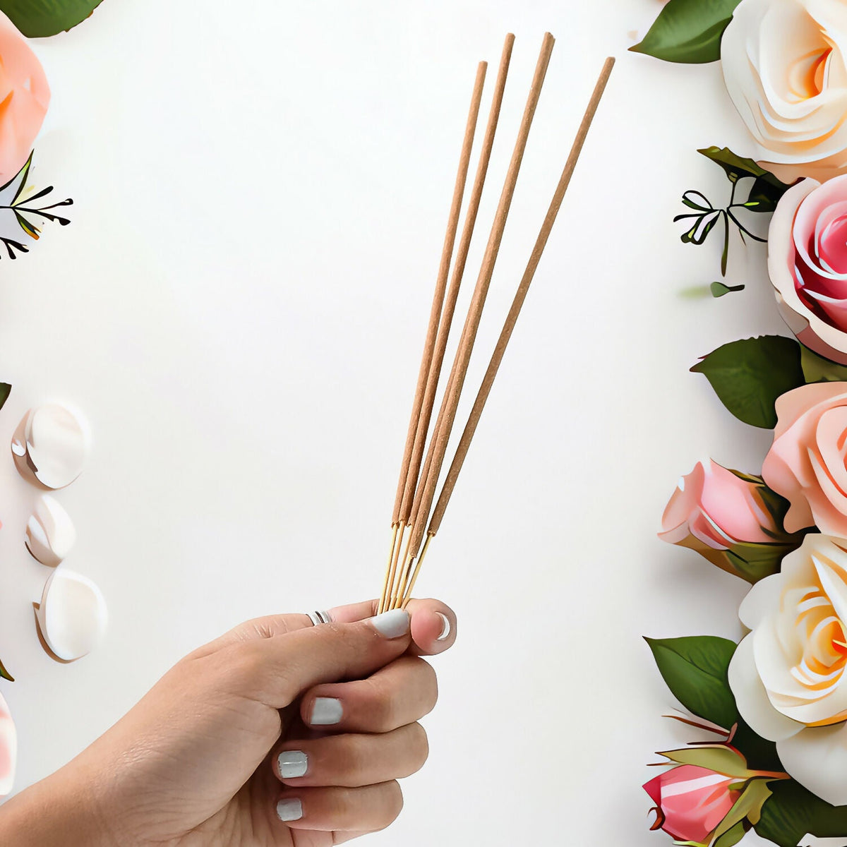 Agarbatti sticks held in hand with flowers
