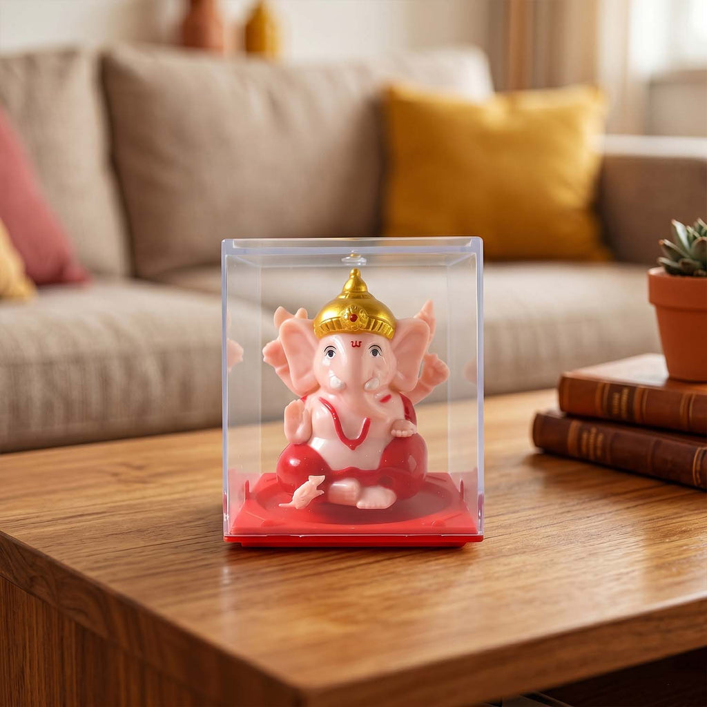 Ganesha idol in glass case beside a candle