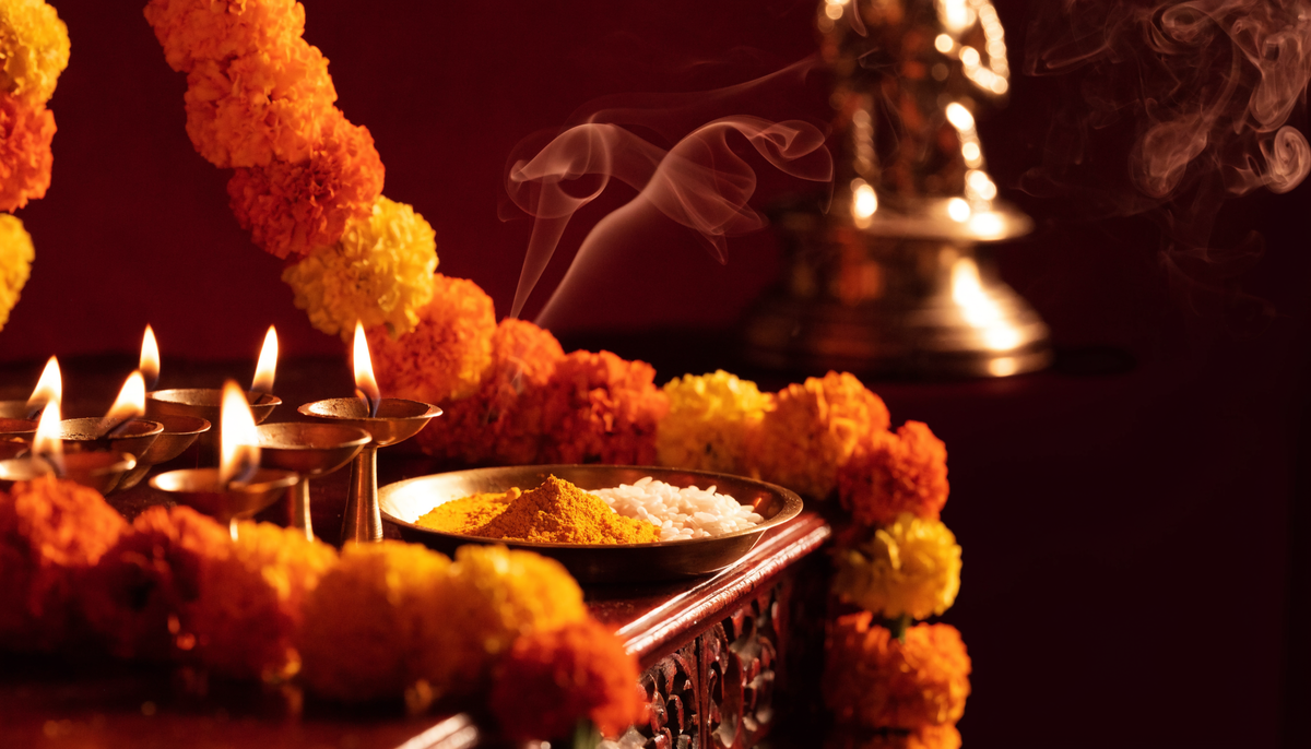 Lit brass diyas, marigold garlands and a pooja thali arranged for a traditional Indian ritual